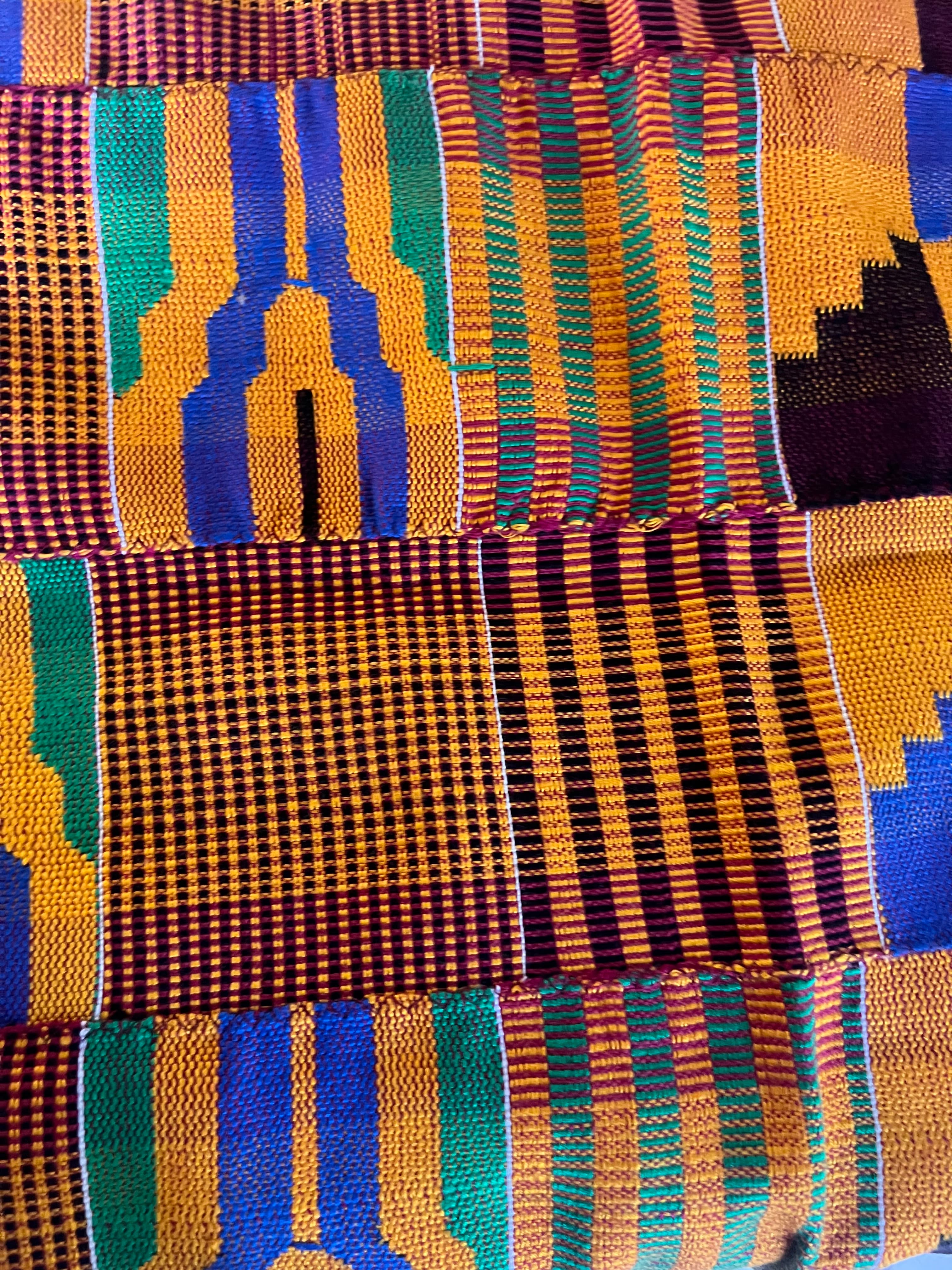 Vibrant Kente cloth featuring intricate geometric patterns in gold, blue, green, and maroon woven together.