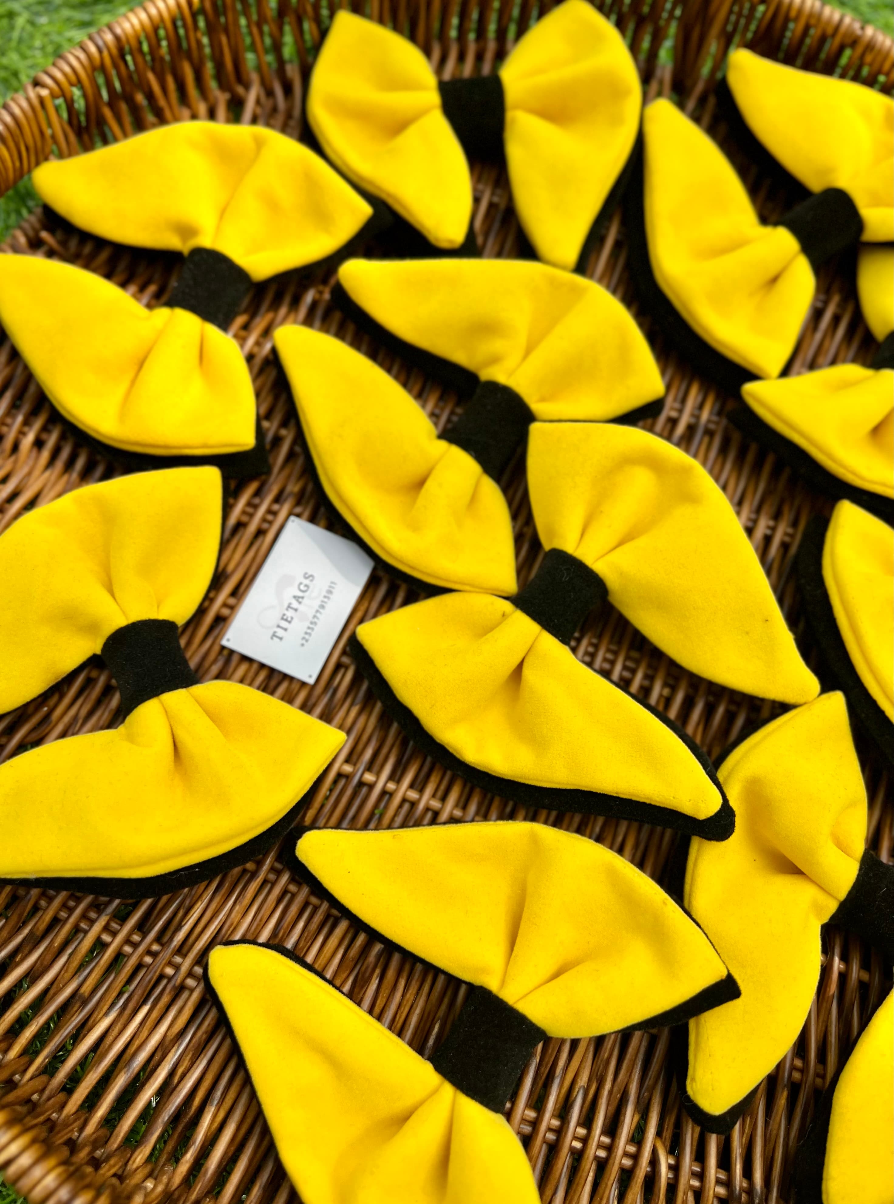 Bright yellow bow ties with black centers resting in a woven brown wicker basket.