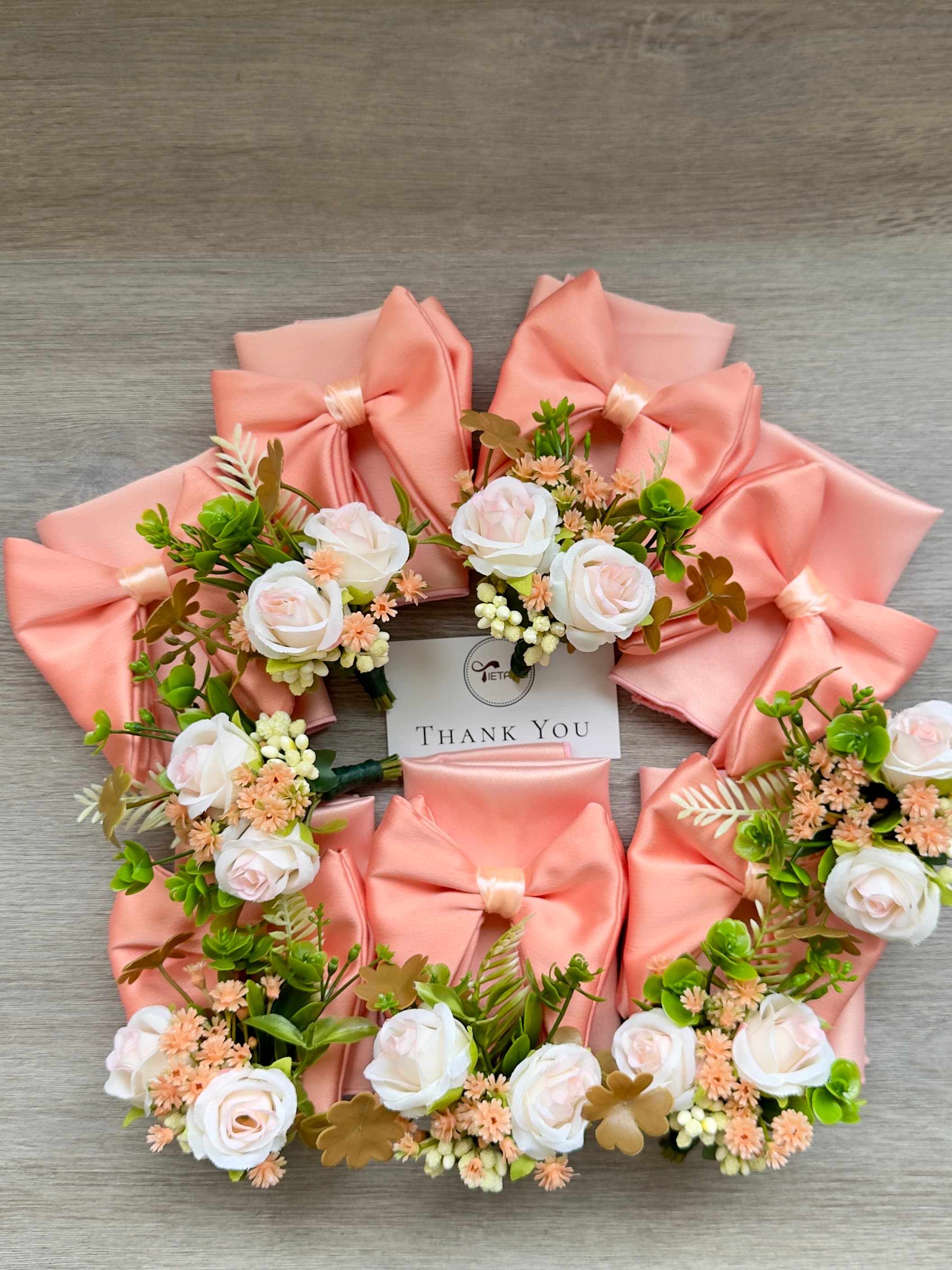 Peach satin bows and white rose boutonnieres arranged around a central "Thank You" card.