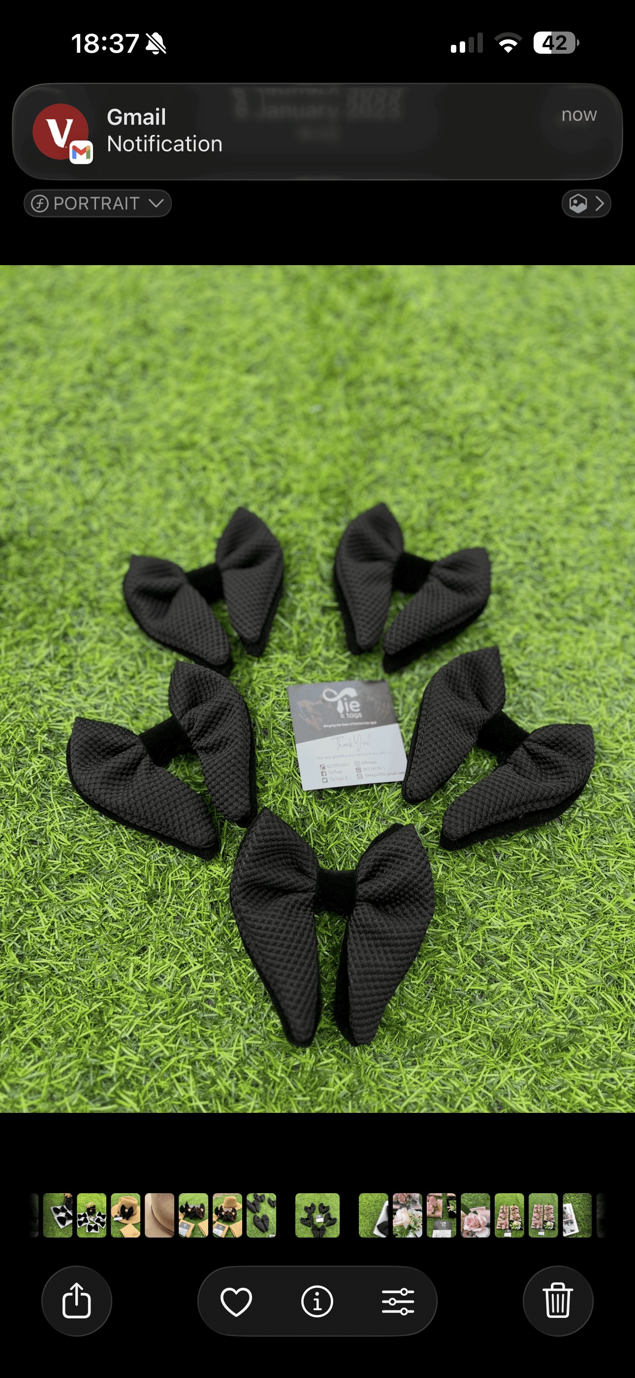 Five black textured bow ties encircling a business card on bright green artificial grass.