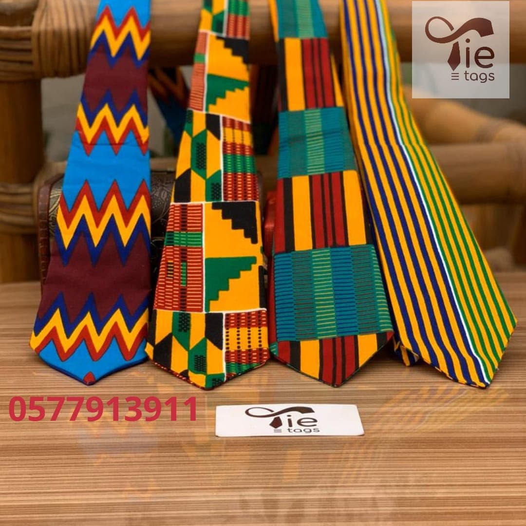 Four neckties featuring bold, colorful African-inspired geometric patterns and stripes on a wooden surface.